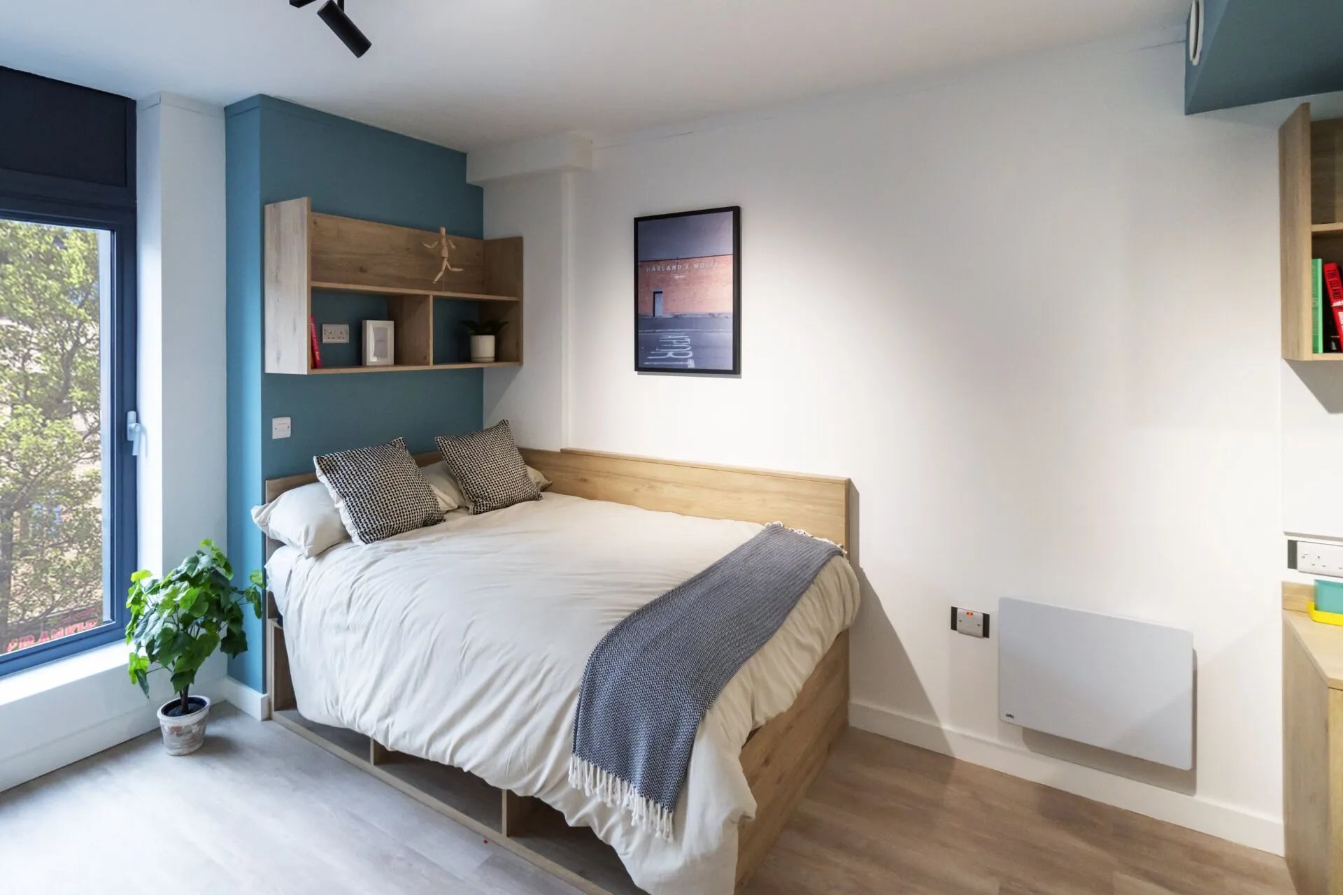 Bed with pillows blanket shelves artwork radiator bedroom at Bradbury Place in Belfast Student Accommodation