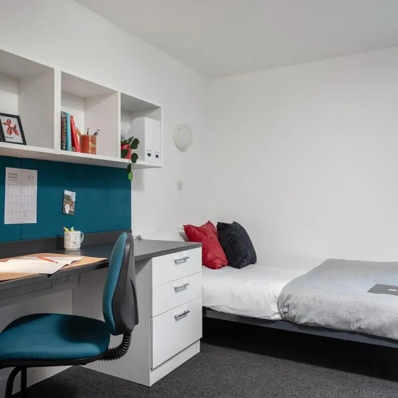 Desk bed chair shelves with books pillows and decor bedroom at Fitzroy Court in Luton Student Accommodation