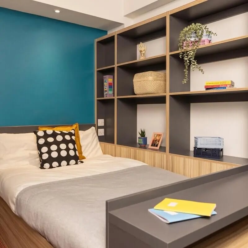 Bed with pillows and grey throw shelving unit Bedroom at Peel Park Quarter in Salford Student Accommodation