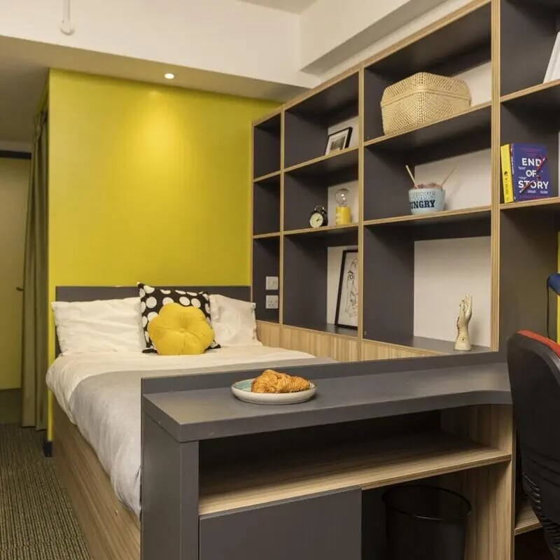 Bed with yellow wall shelves and desk bedroom at Peel Park Quarter in Salford Student Accommodation