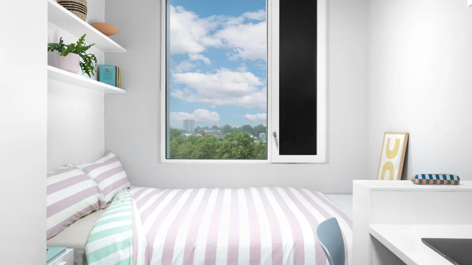 Striped bed shelves plant and picture bedroom at Scape Canada Water in London Student Accommodation