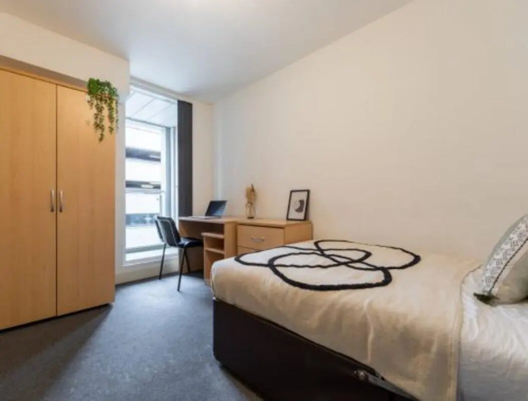 Wardrobe desk chair bed with patterned throw Bedroom at The Grafton in Manchester Student Accommodation