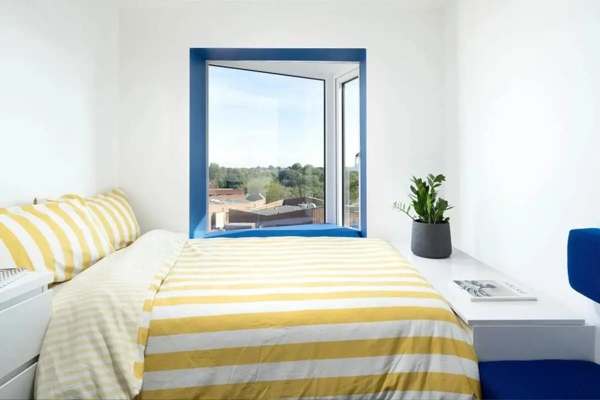 Bed with yellow striped duvet blue chair bedroom at Scape Guildford in Guildford Student Accommodation