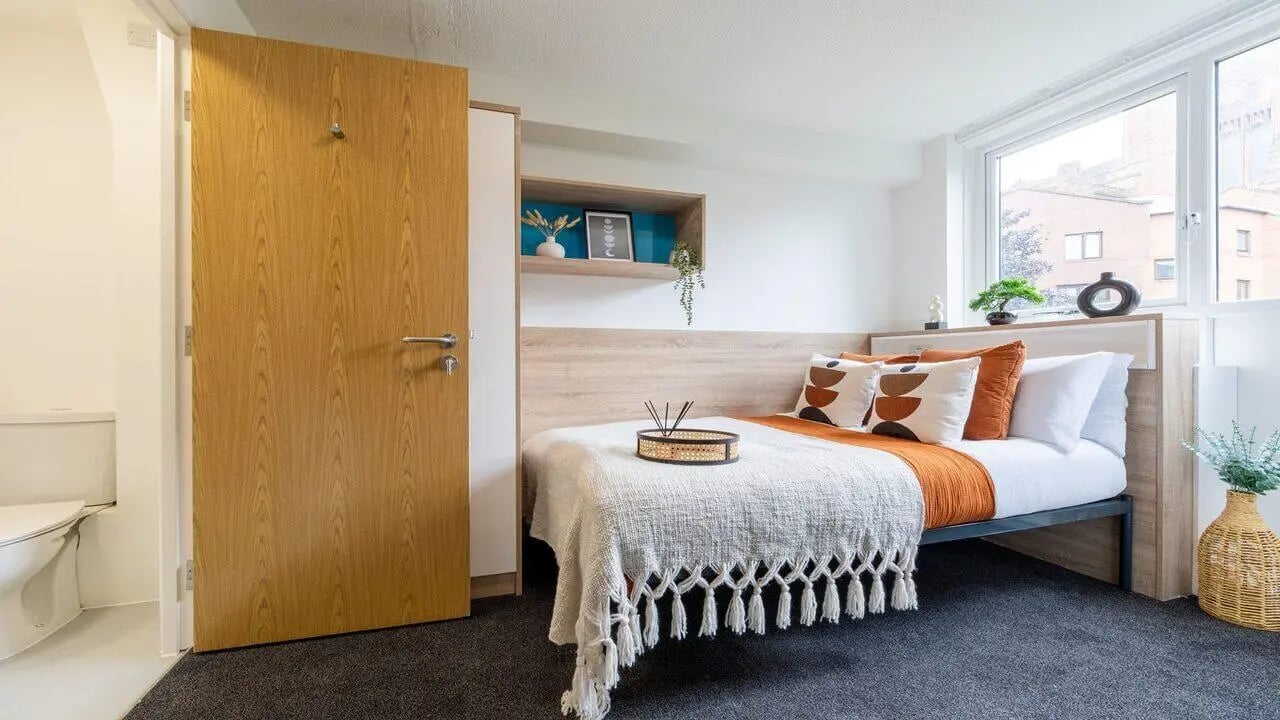 Bed with orange pillows and white blanket bedroom at dwell Cathedral Campus in Liverpool Student Accommodation