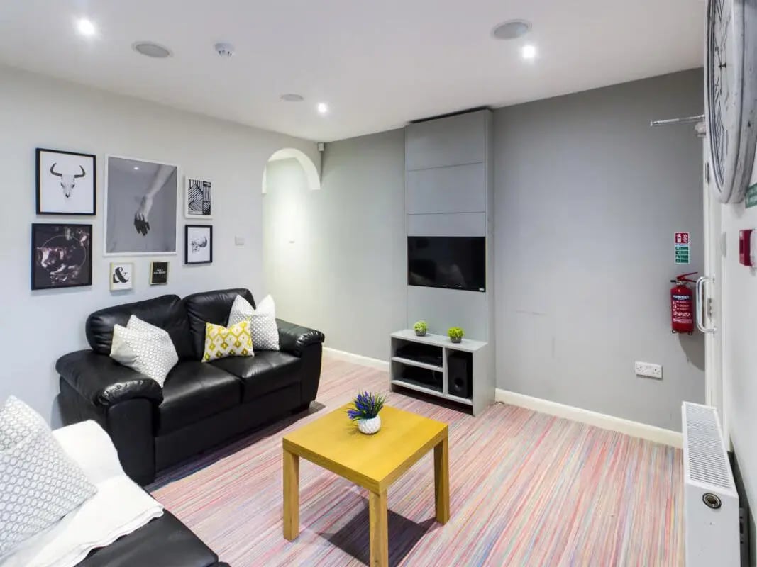 Black sofas coffee table artwork wall mounted TV living room at 210 Cauldon Road in Stoke-On-Trent Student Accommodation