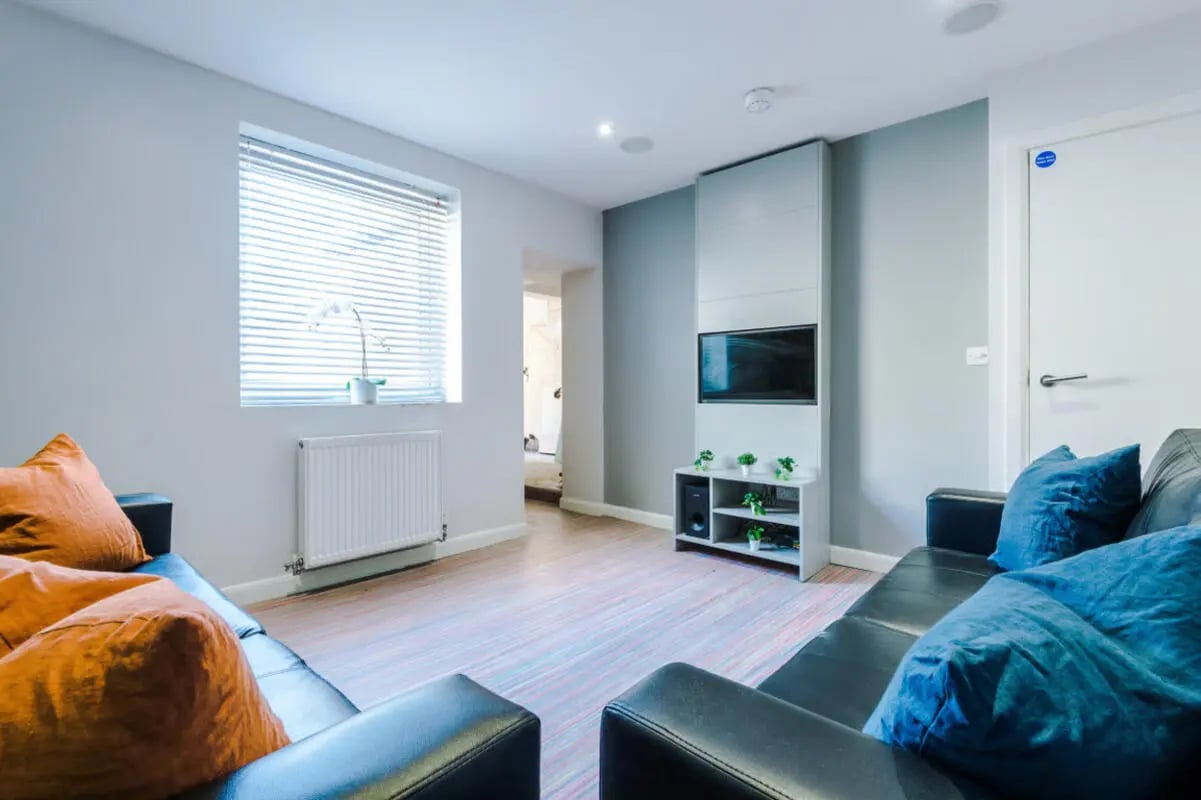 Black couches with orange and blue pillows living room at 9 Queen Anne Street in Stoke-On-Trent Student Accommodation
