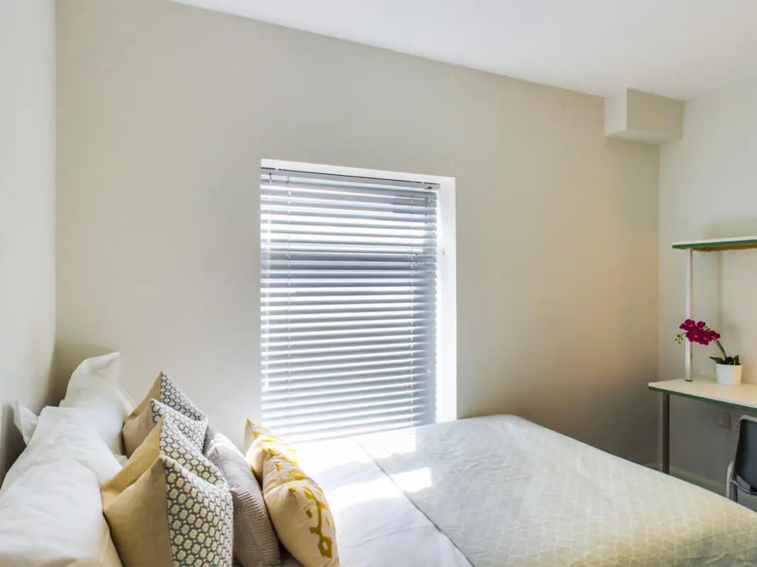 Bed with pillows blinds desk and flower bedroom at 21 Queen Anne Street in Stoke-On-Trent Student Accommodation