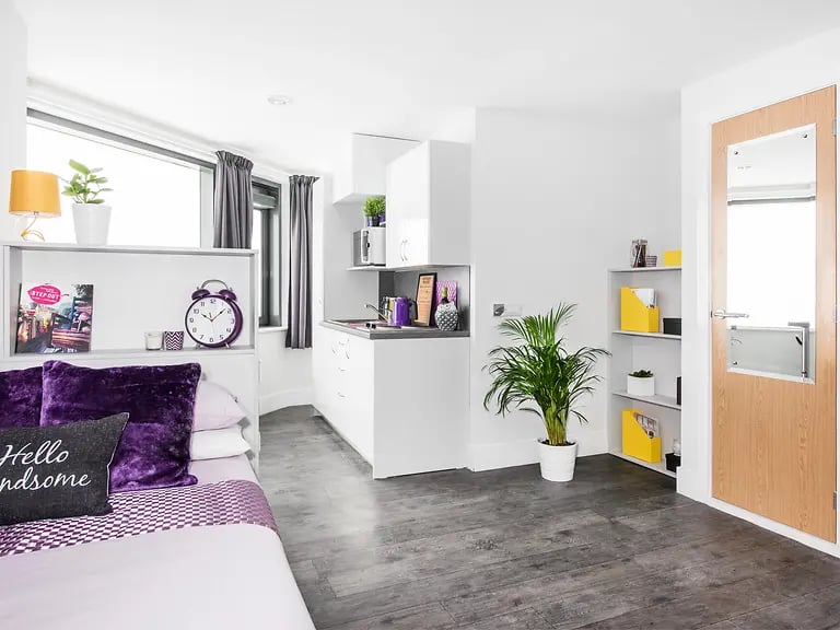 Bed purple pillows alarm clock kitchenette kitchen area at Yugo Ablett House in Liverpool Student Accommodation