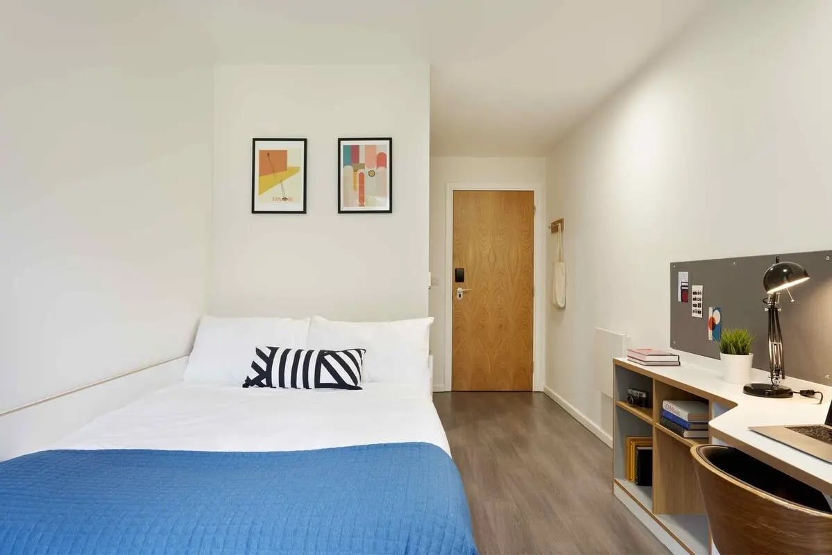 Bed with striped pillow desk and shelves bedroom at Asa Briggs House in Leeds Student Accommodation