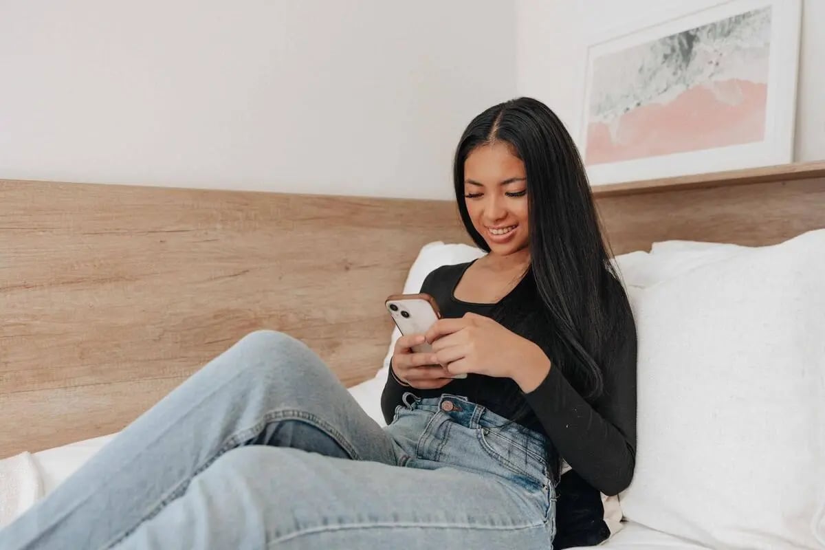 Woman on bed with phone bedroom at Bailey Fields -Sheffield in Sheffield Student Accommodation