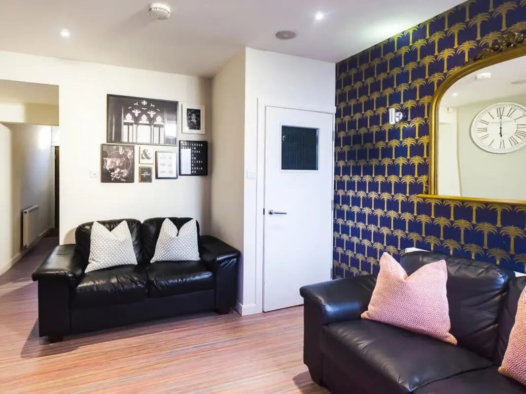 Black sofas framed photos and palm wallpaper living room at 42 Watford Street in Stoke-On-Trent Student Accommodation