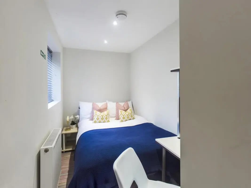 Bed with blue blanket and decorative pillows bedroom at 30 Watford Street in Stoke-On-Trent Student Accommodation