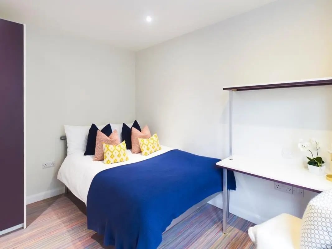 Bed with blue blanket desk and pillows bedroom at 233 Leek Road in Stoke-On-Trent Student Accommodation