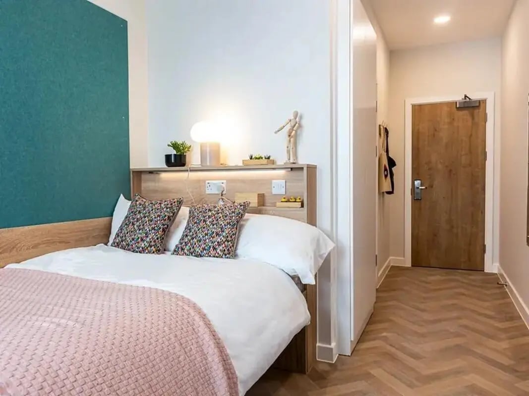 Bed with patterned pillows pink throw and decor Bedroom at Yugo St. Crispin's House in Norwich Student Accommodation