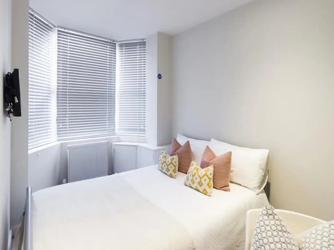 Bed with patterned pillows white bedding blinds bedroom at 123 Leek Road in Stoke-On-Trent Student Accommodation