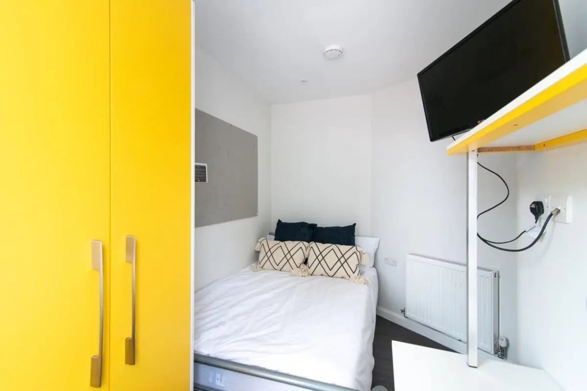 Yellow wardrobe bed TV and corkboard bedroom at 231 Leek Road in Stoke-On-Trent Student Accommodation