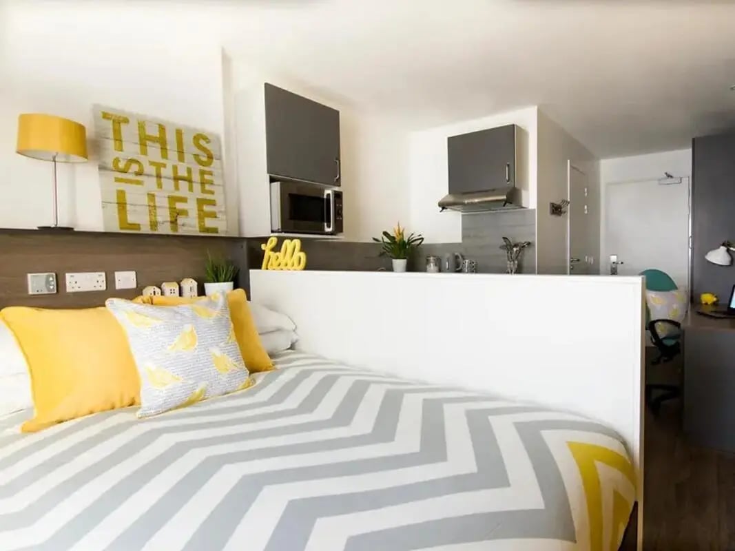 Bed with yellow pillows and chevron bedding studio at Yugo Beckley Point in Plymouth Student Accommodation
