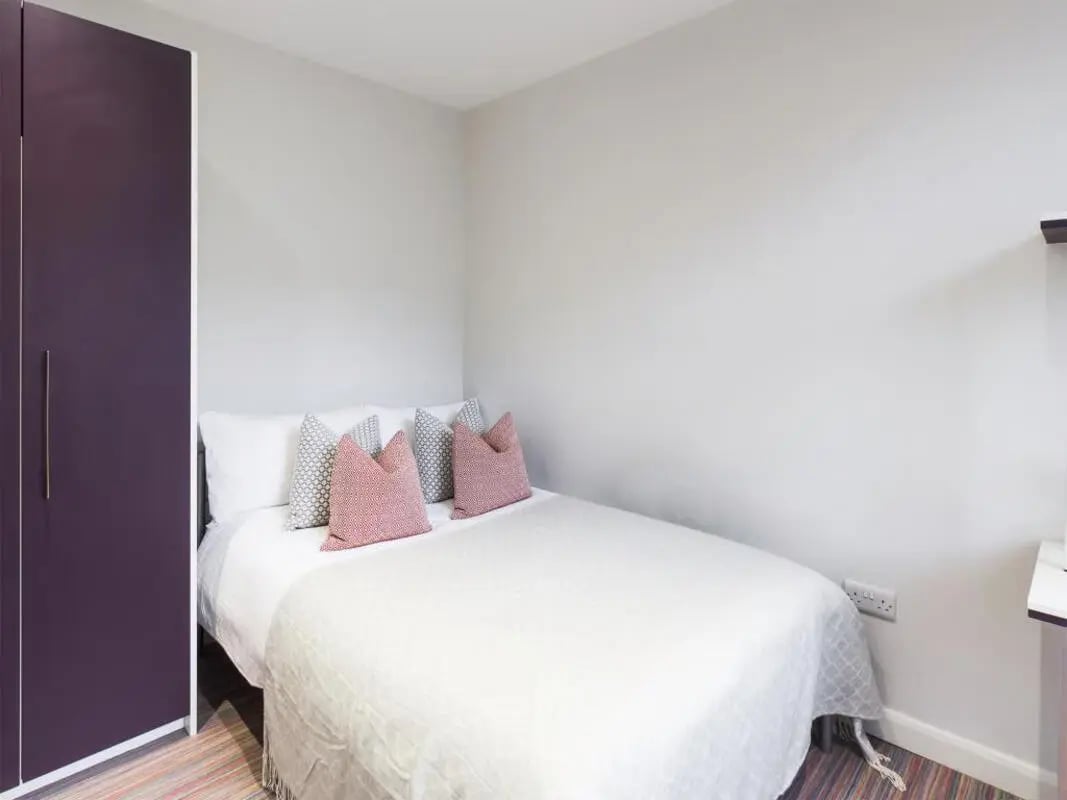 Purple wardrobe white bed decorative pillows bedroom at 6 Cauldon Road in Stoke-On-Trent Student Accommodation