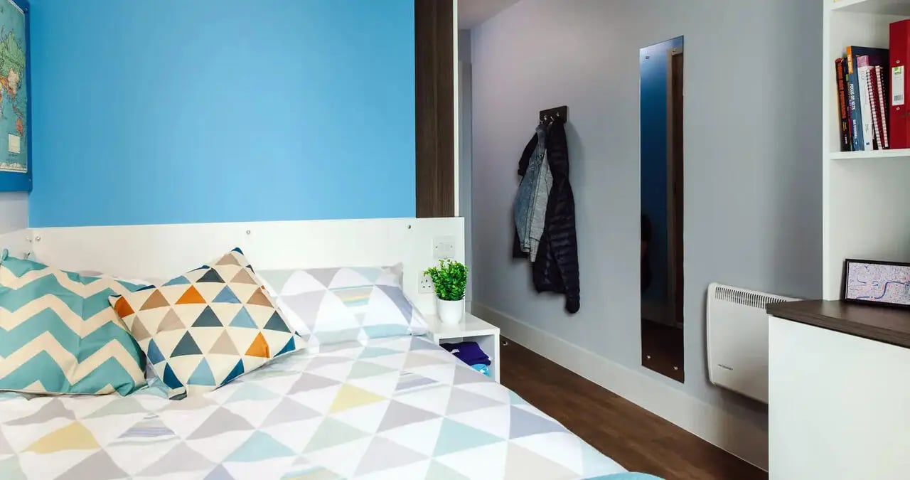 Bed with patterned pillows and coats bedroom at Kaplan Living Bournemouth in Bournemouth Student Accommodation