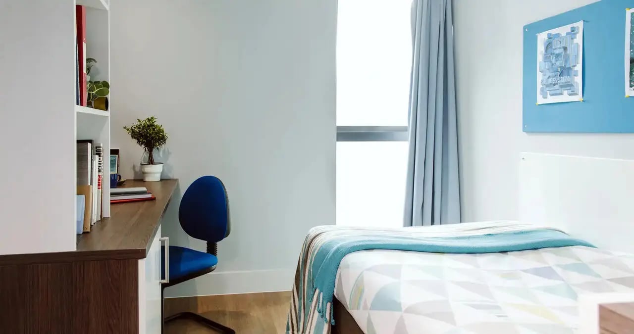 Bed desk bookshelf blue chair bedroom at Kaplan Living Bournemouth in Bournemouth Student Accommodation