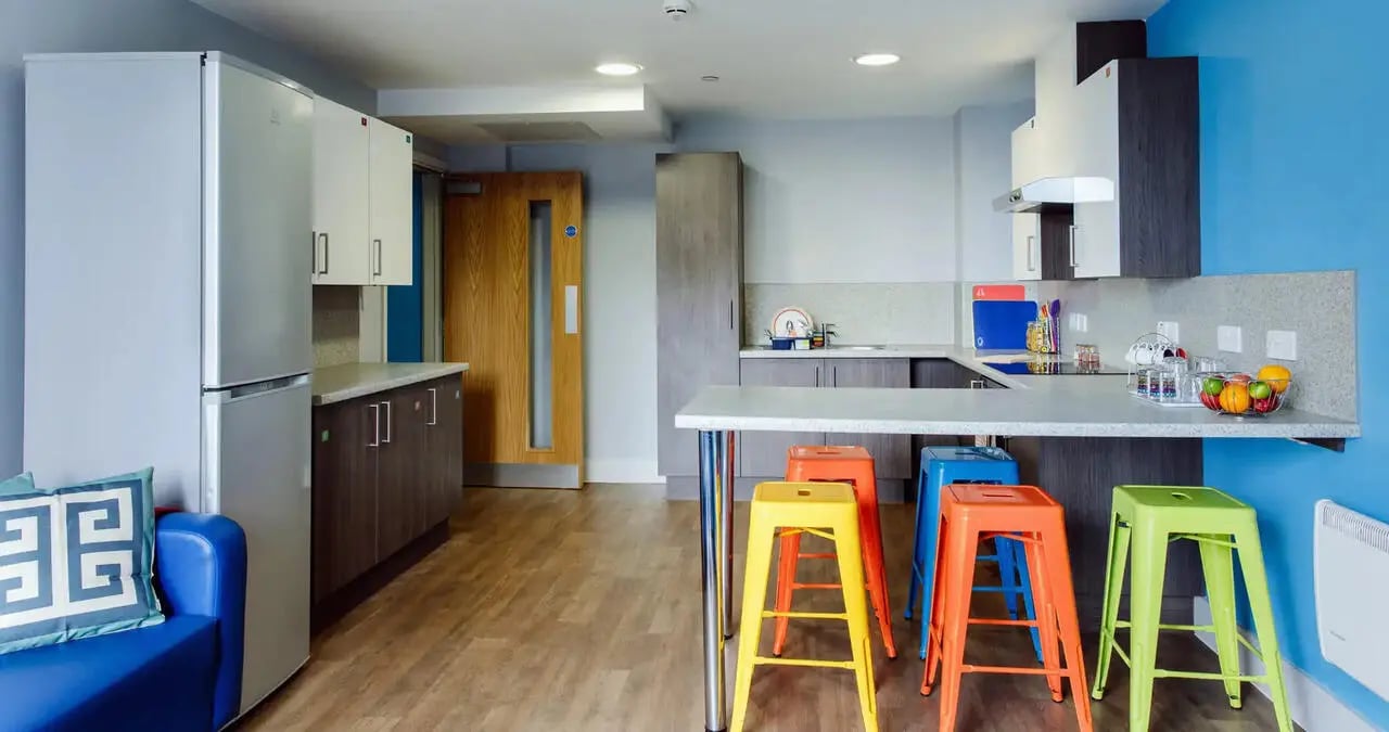 Kitchen with blue couch stools and appliances kitchen at Kaplan Living Bournemouth in Bournemouth Student Accommodation