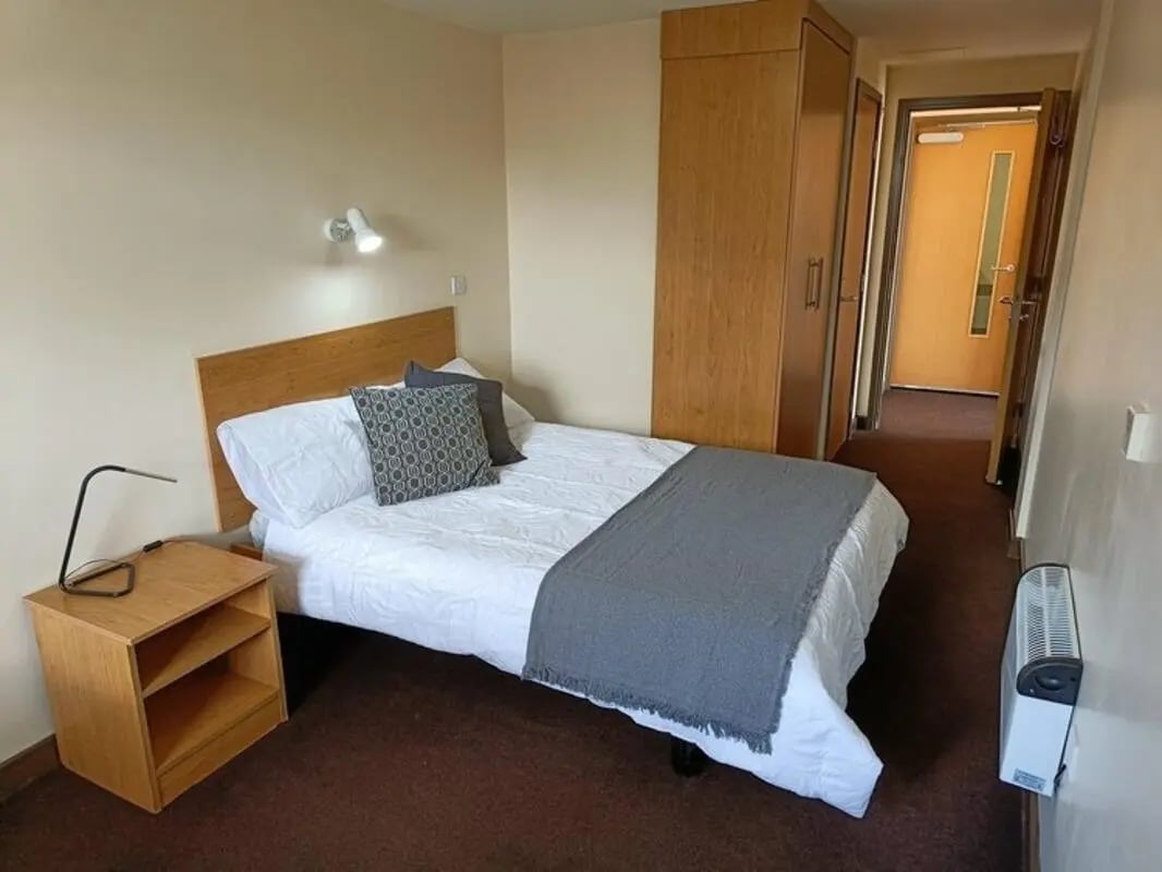Bed wardrobe nightstand and open door bedroom at Asha House in Loughborough Student Accommodation