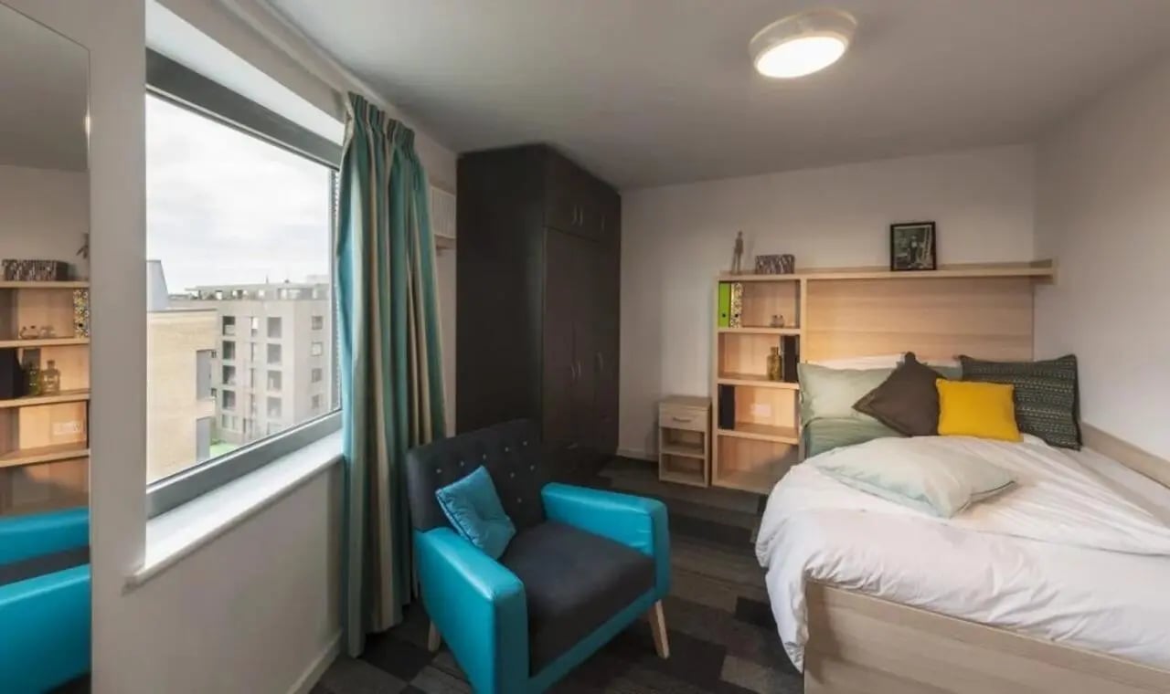 Bed armchair wardrobe shelves and window bedroom at The Railyard Cambridge in Cambridge Student Accommodation