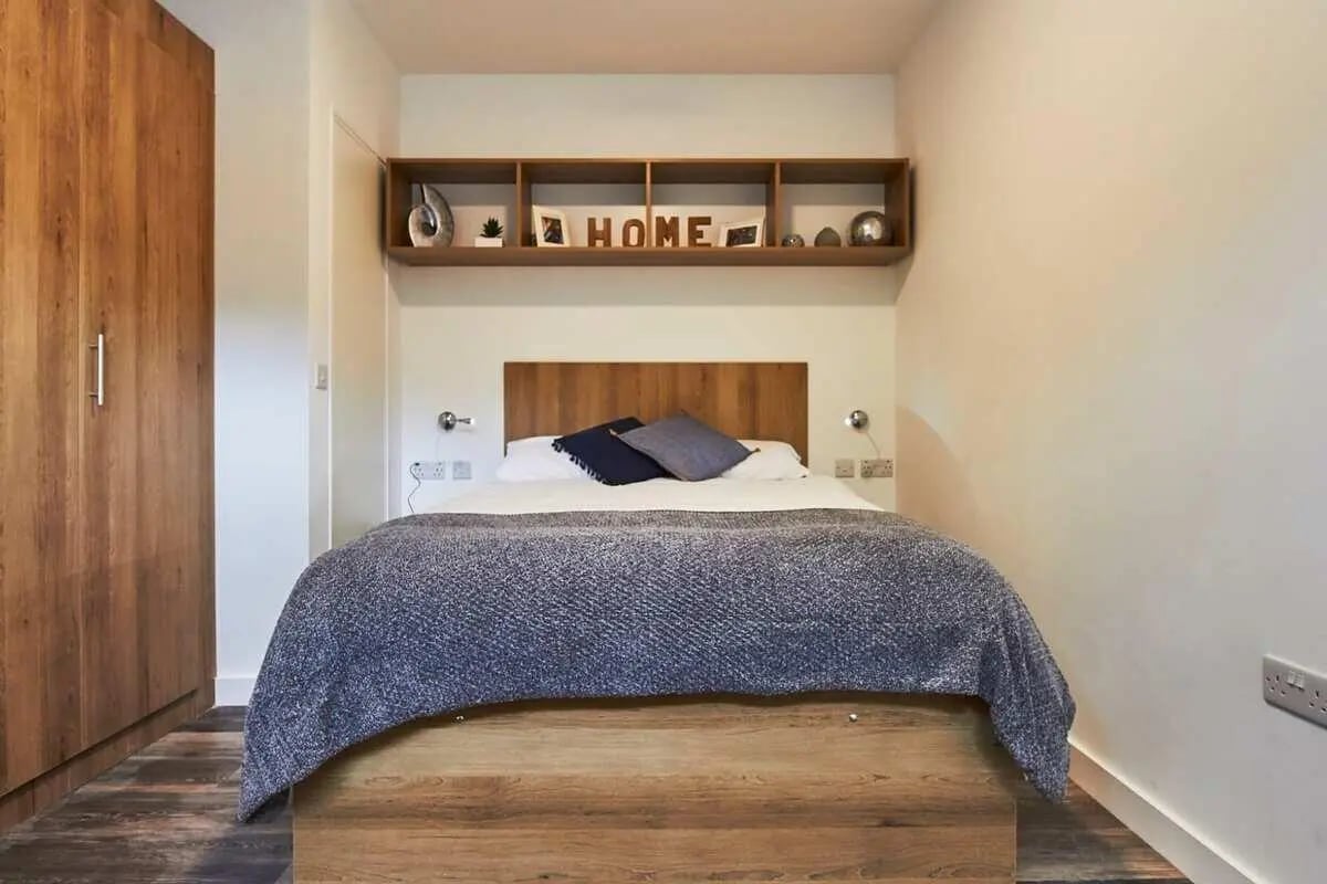 Bed with wooden headboard and shelves above bedroom at City Heights - Cardiff in Cardiff Student Accommodation