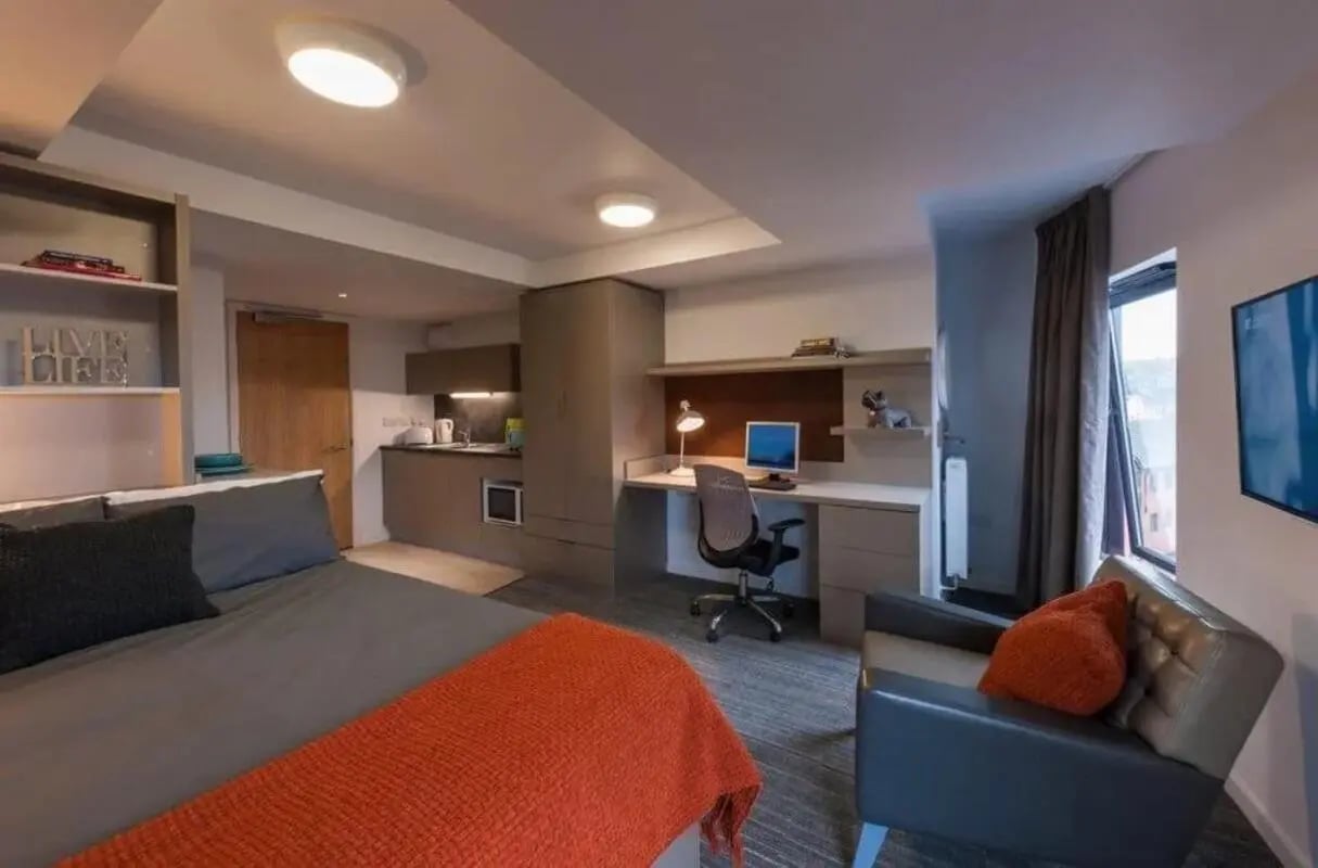 Bed desk kitchen area chair and TV living room at West Village in Glasgow Student Accommodation