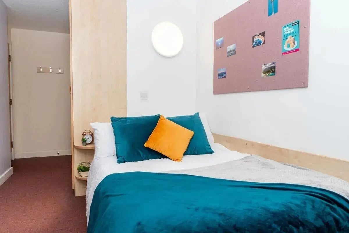 Bed with blue teal and orange pillows bedroom at Wardley House in Bradford Student Accommodation