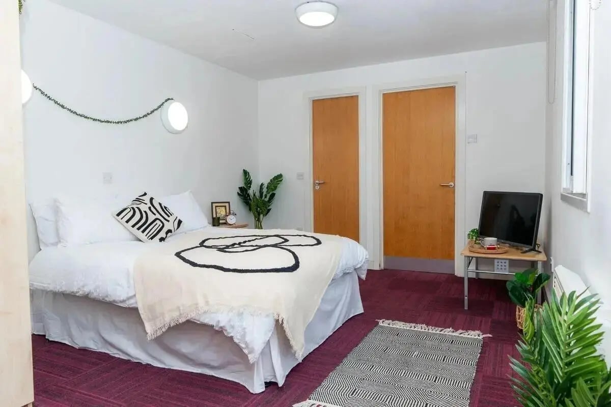 Bed with plants and television bedroom at Wardley House in Bradford Student Accommodation