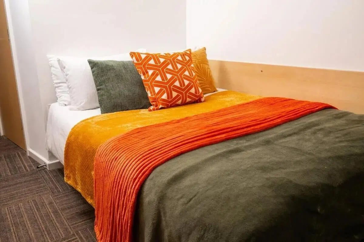 Bed with white pillows orange and green blankets bedroom at Marybone Student Village 2 in Liverpool Student Accommodation