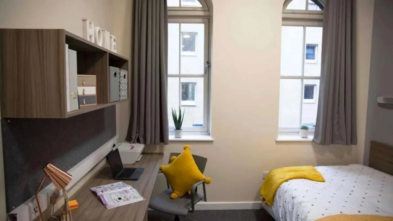 Desk bed shelves and windows bedroom at Lilian Knowles House in London Student Accommodation