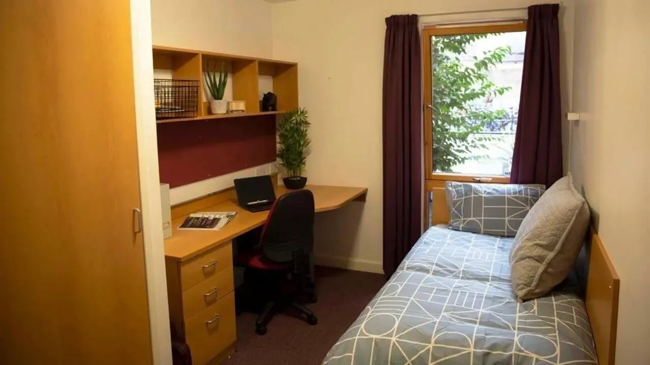 Bed desk shelves and chair student room at Lilian Knowles House in London Student Accommodation