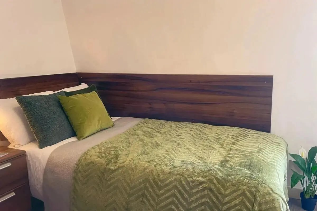 Bed with green quilt and pillows bedroom at The Craft Building in London Student Accommodation