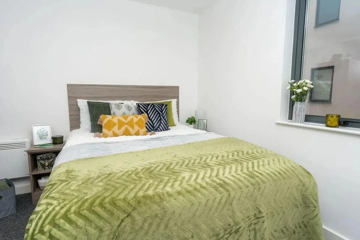 Bed with green chevron blanket and pillows bedroom at Grafton Street in Manchester Student Accommodation