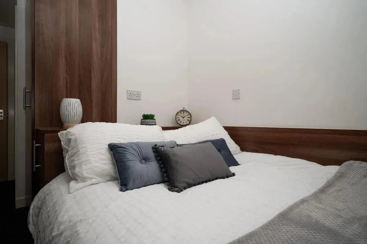 Bed with pillows vase clock and plant Bedroom at Walker Street in Preston Student Accommodation