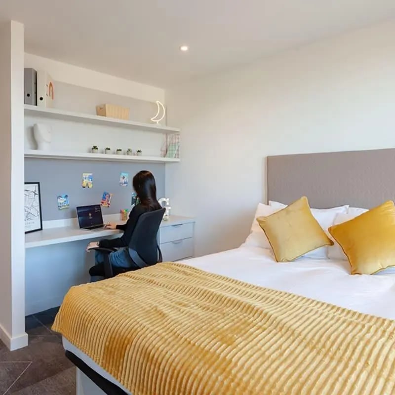Student sitting at desk with laptop bedroom at True Glasgow in Glasgow Student Accommodation