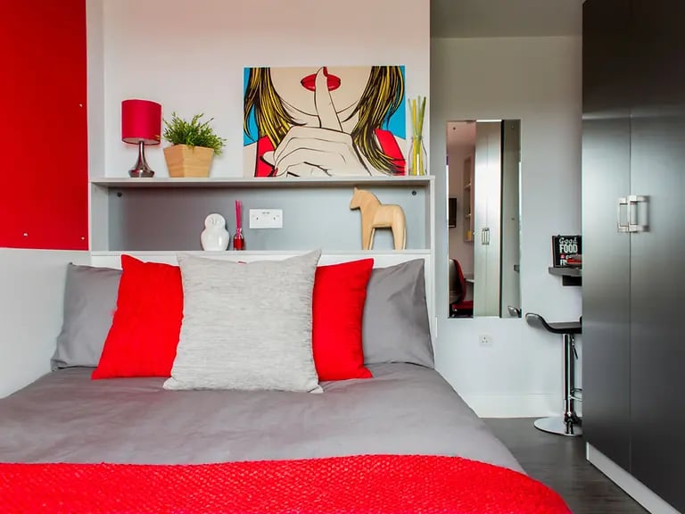Bed with red pillows and artwork bedroom at Yugo Arran House in Edinburgh Student Accommodation