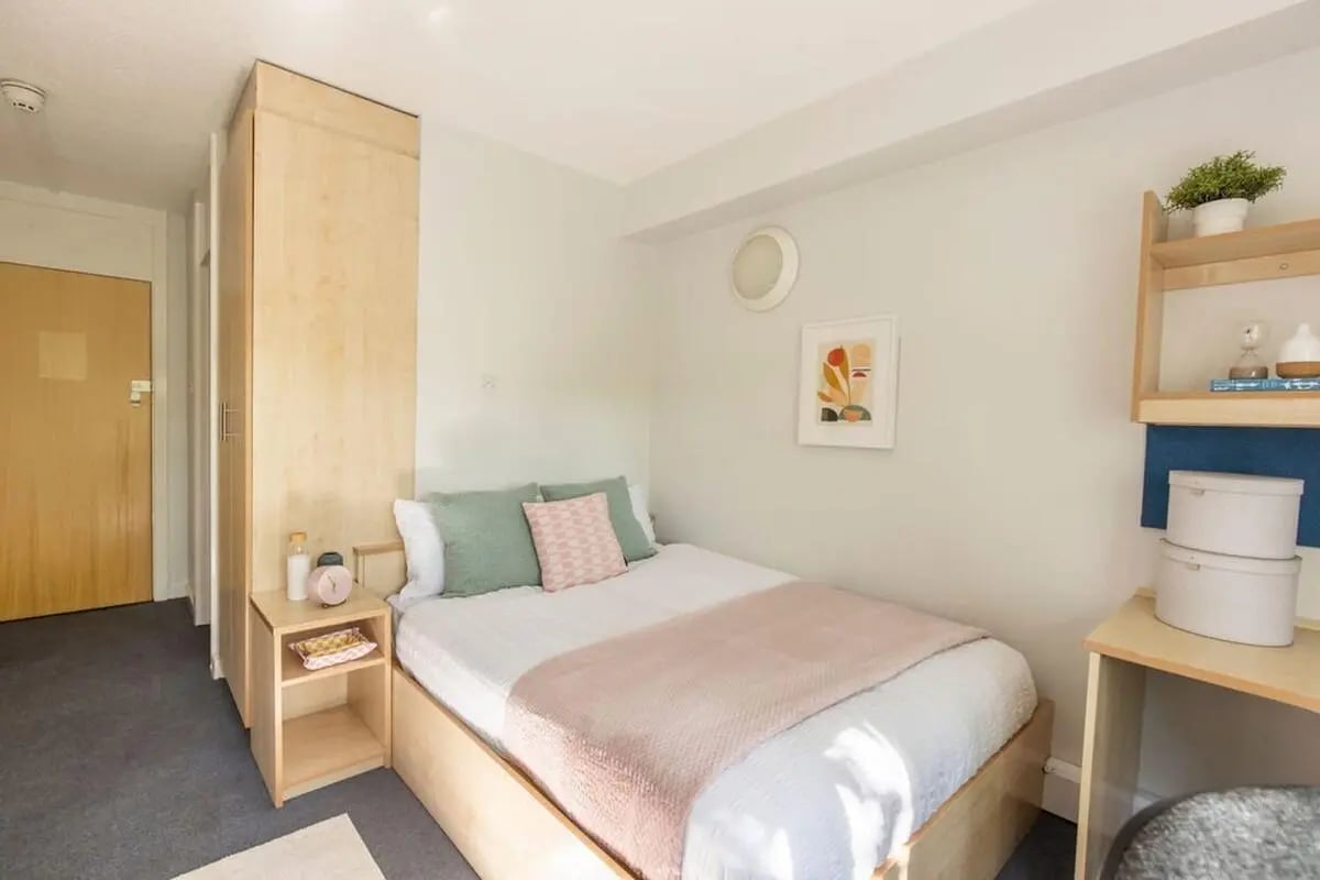 Bed with pink throw green pillows and nightstand Bedroom at Charlotte Court in Sheffield Student Accommodation