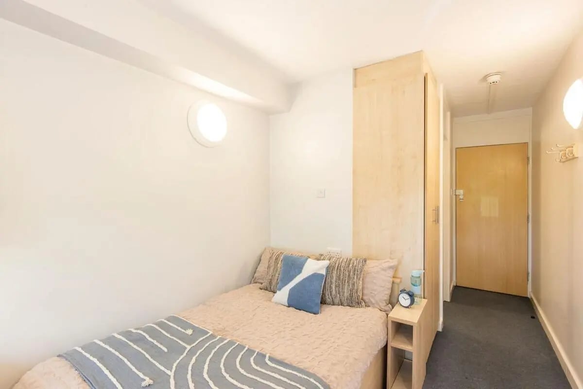 Bed with pillows and blanket near wardrobe and door bedroom at Charlotte Court in Sheffield Student Accommodation