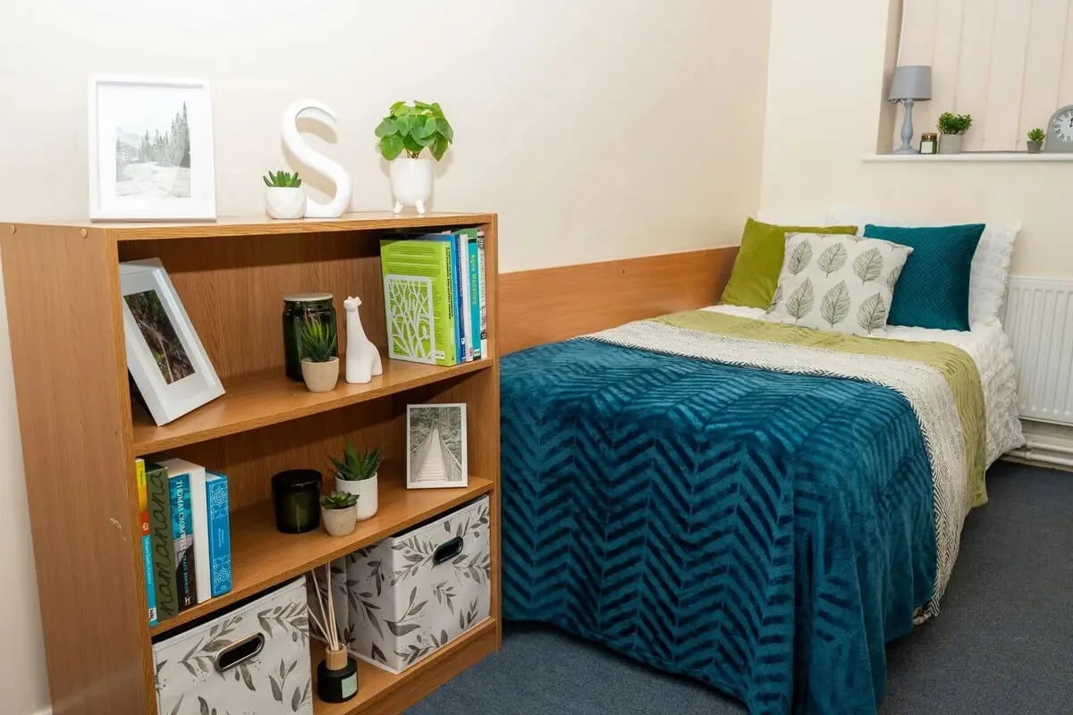 Bed with patterned throw bookshelf with decor bedroom at Grange Court & The Ridings in Ormskirk Student Accommodation