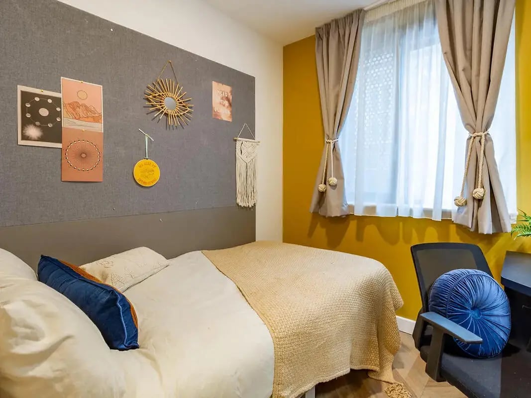 Bed with blue pillow yellow blanket and mirror Bedroom at Yugo Belaton House in Bournemouth Student Accommodation