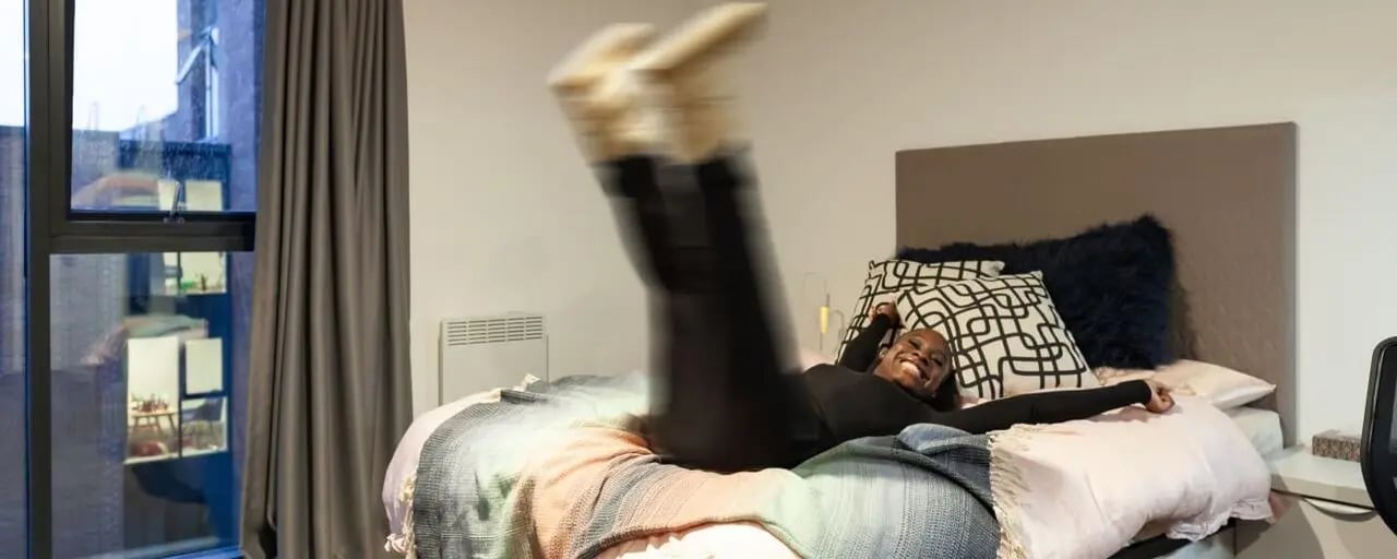 Bed with person jumping plaid blanket bedroom at True Liverpool in Liverpool Student Accommodation