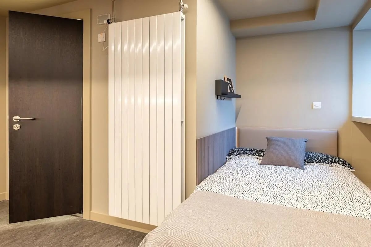 Dark door white radiator bed with pillows Bedroom at Potterrow in Edinburgh Student Accommodation