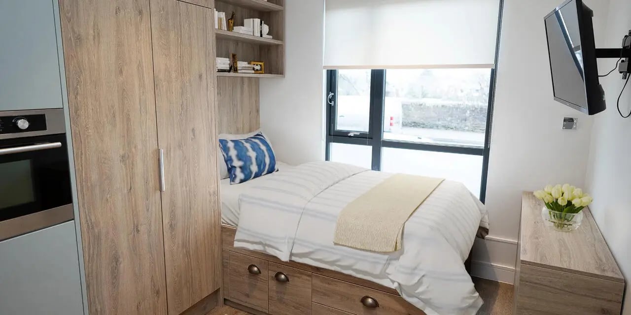 Bed with striped bedding blue pillow and drawers bedroom at Canvas Student - Quintana Gate in Exeter Student Accommodation