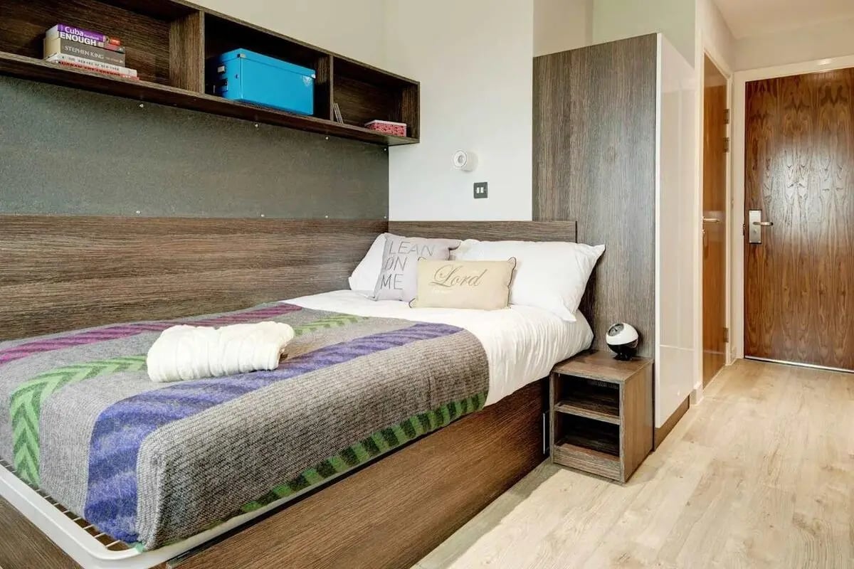 Bed with patterned blanket nightstand and door bedroom at Cricket Field Court in Exeter Student Accommodation