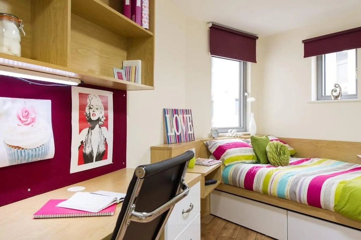 Desk bed shelves colorful bedding bedroom at Quebec House in Kingston Upon Thames Student Accommodation