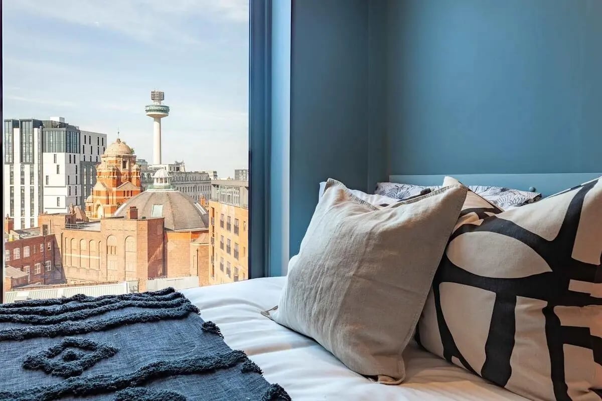 Bed with city view and decorative pillows Bedroom at Benson Yard in Liverpool Student Accommodation