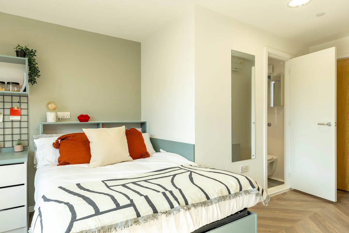 Bed with pillows shelving and ensuite bathroom bedroom at The Brook in Bath Student Accommodation